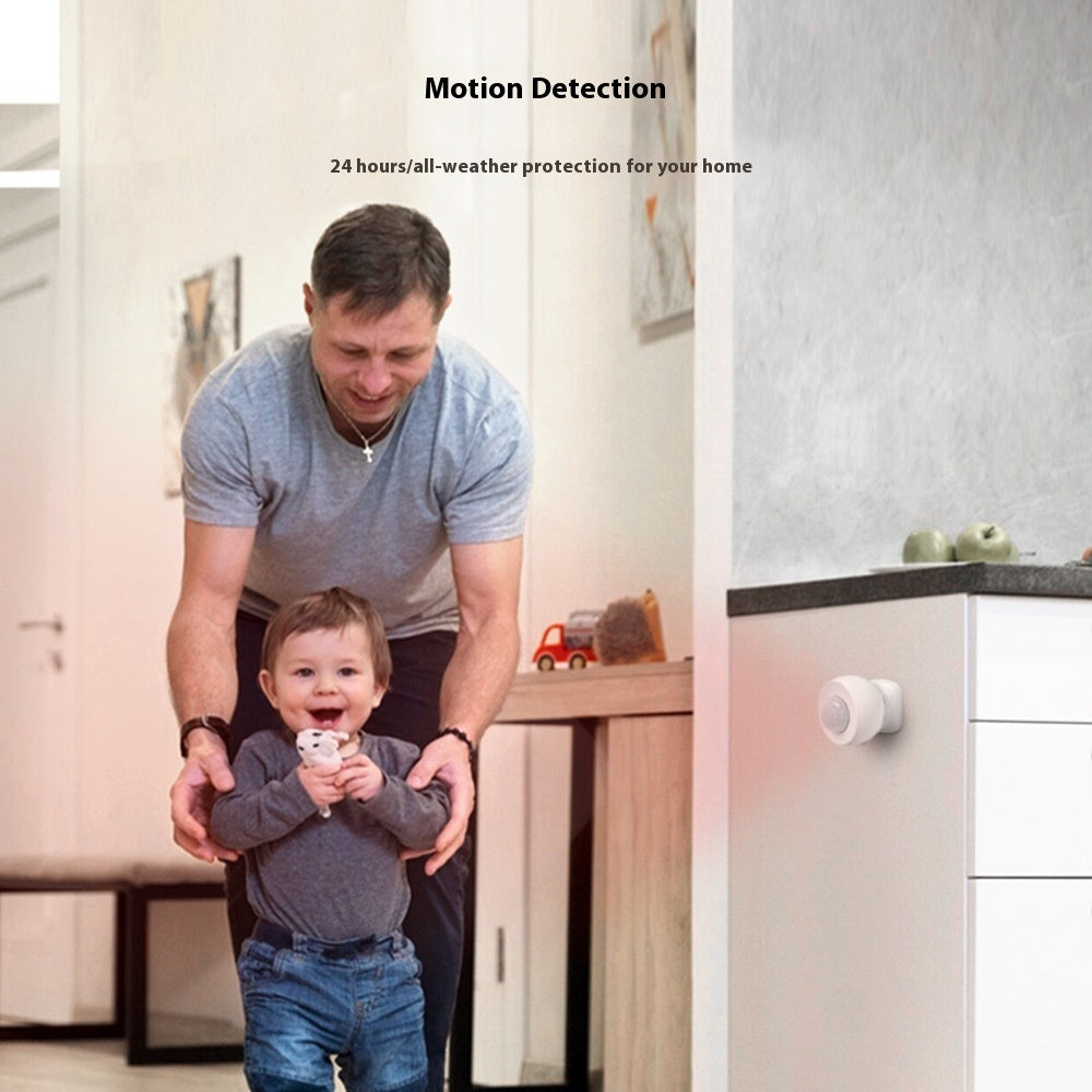 Man holding a child with a security device on a kitchen counter, emphasizing motion detection for home security.
